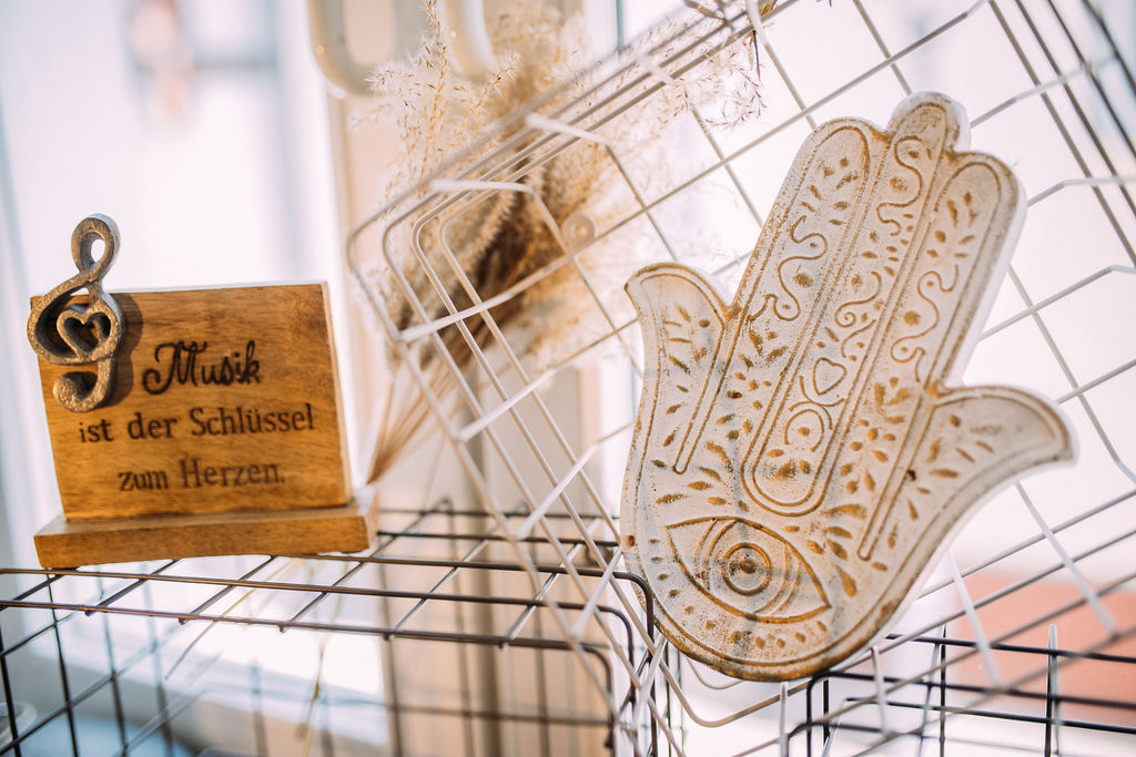 Holzschild „Musik ist der Schlüssel zum Herzen“ neben einer Hamsa-Hand